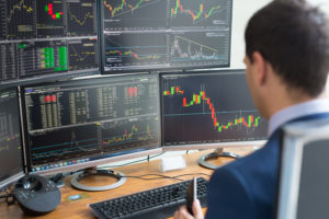 Over the shoulder view of computer screens and stock broker trading online.